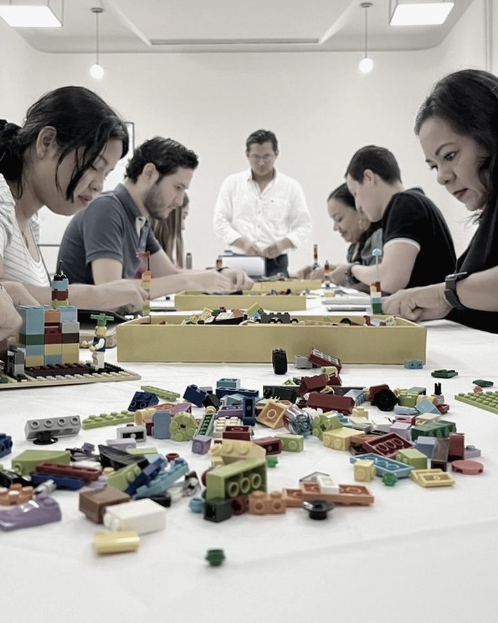 Mesa de trabajo con modelos construidos por el equipo y piezas extendidas sobre la superficie.